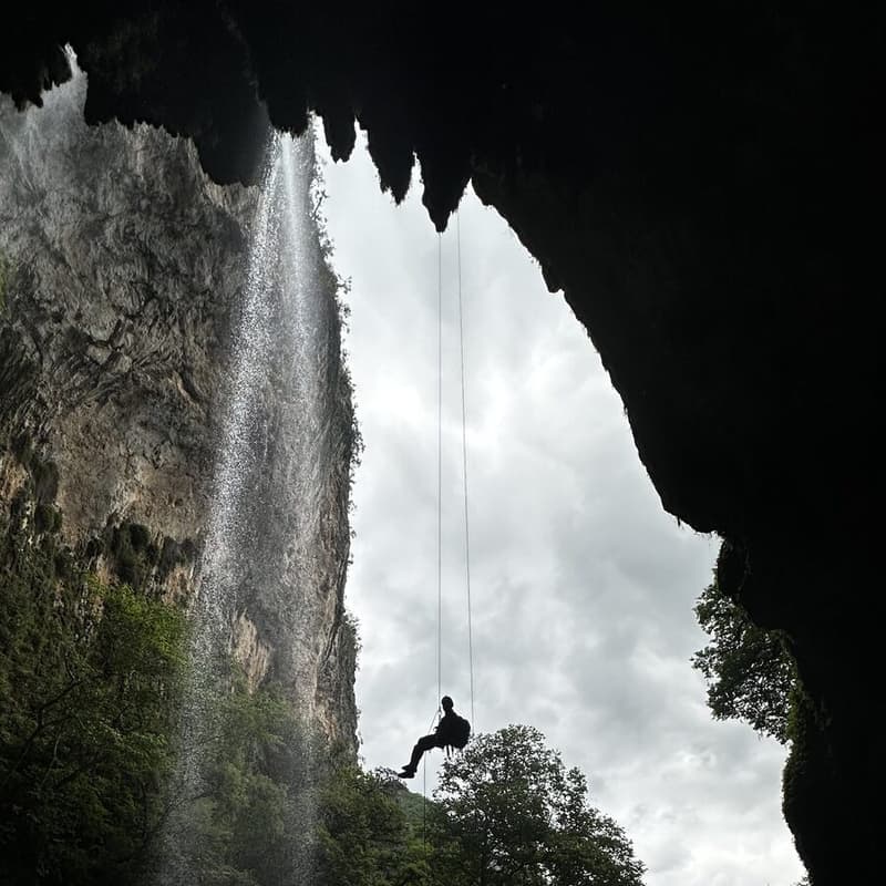 Persona en rappel colgando junto a la cortina de agua de la Cascada del Chipitín