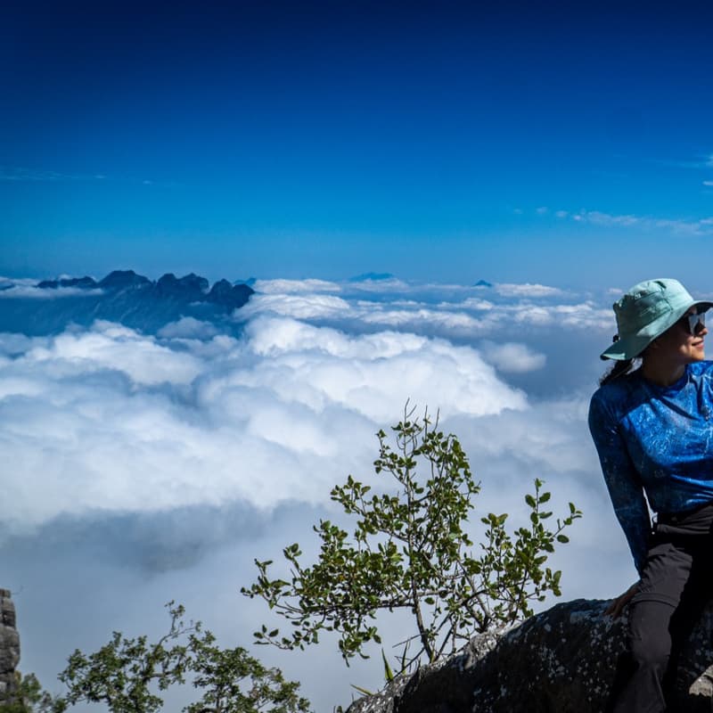 Excursionista sentada en la roca de la cumbre del Copete de las Águilas, sobre un mar de nubes